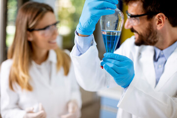 Researcher working with blue liquid at separatory funnel