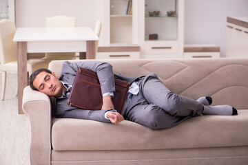 Fototapeta premium Tired young businessman coming home after working day