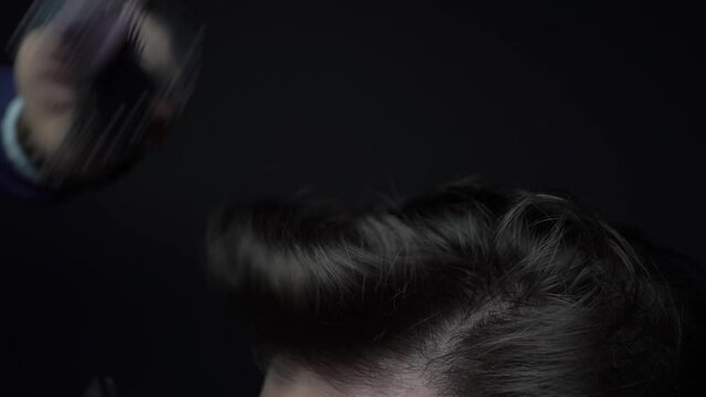Master hairdresser makes styling with hair dryer and hairbrush
