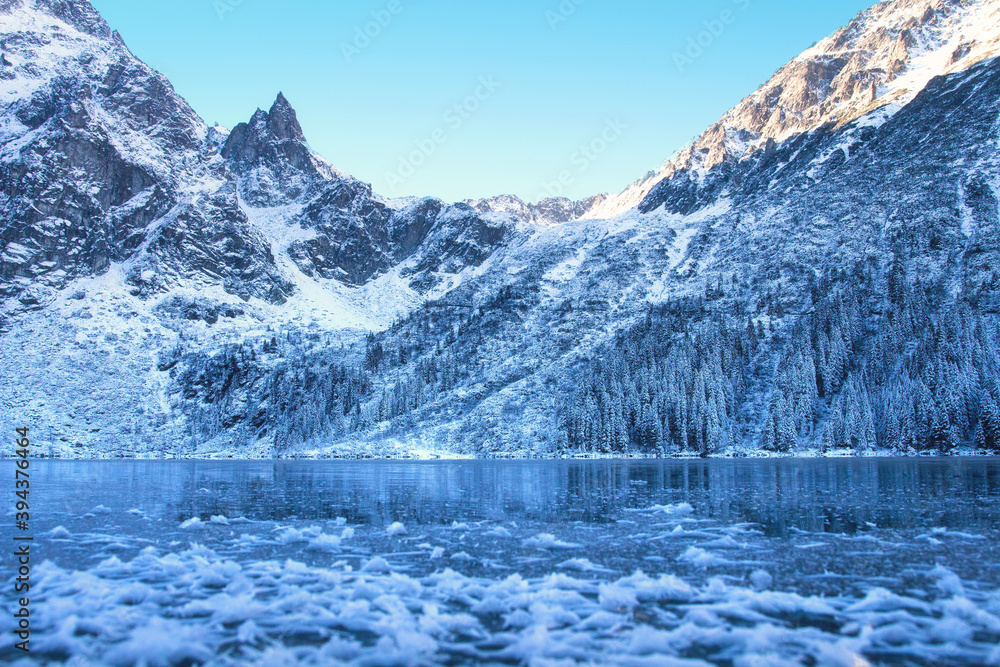 Wall mural Ice winter mountain lake. Amazing frozen rocky mountains on the lakeshore. Winter background. Winter nature.