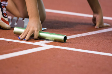Starting position for relay race on the treatmill on the stadium. Baton in hand