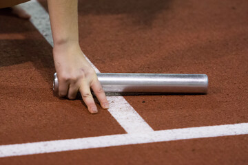 Starting position for relay race on the treadmill on the stadium. Silver color baton in hand