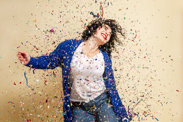 Fototapeta na wymiar Laughing young brunette girl sprinkled with confetti. Festive mood. New Year's and Christmas. Yellow background.