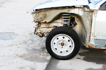 Fototapeta premium Rusty car on a city street. Close-up view of the front of a car badly damaged in another car accident. on a gray rusty car body. Negligence towards the car. Lack of anti-corrosion treatment, the