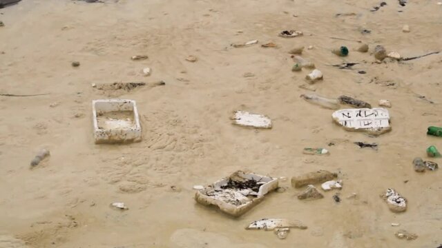 Closeup of sea foam with flooting garbage, plastic bottles and pieces of polystyrol in the ocean.