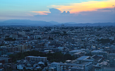 Aerial late afternoon view of the southwest Tokyo suburbs stretching towards the mountains on a partly cloudy day