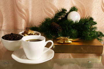 A cup of coffee on the table against the background of New Year's decor. Cup of coffee with Christmas decor on the table.