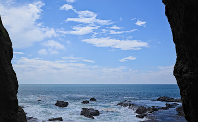 View of the ocean and a rocky shoreline on a partly cloudy day from Enoshima Iwaya Cave
