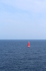 Lonely yacht with red sails in the Mediterranean sea