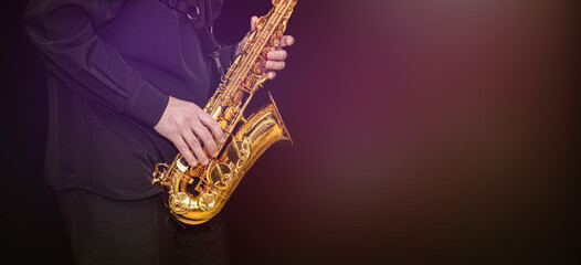 Naklejka premium Saxophone Player hands Saxophonist playing jazz music. Alto sax musical instrument closeup on black background with gradient light