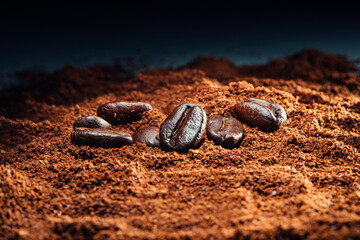 Close up roasted coffee beans on ground coffee, pile of powdered or instant coffee