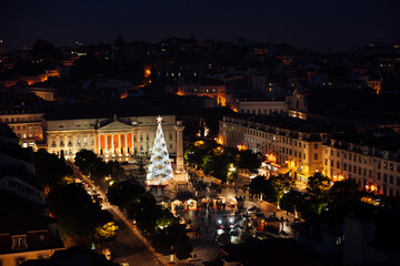 Night cityscape of Rossio square in Lisbon during festive Christmas time shot from above. Christmas tree at a South European city illuminated with electric lights