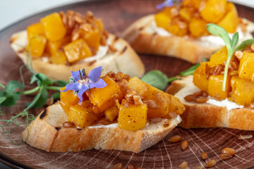 Bruschetta with grilled pumpkin, cheese and pearl barley on toasted bread on a plate, close up