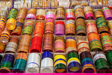 Rows of traditional colorful glass bangles and bracelets are displayed for sale.