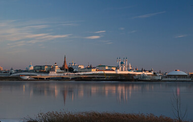 Obraz na płótnie Canvas The Kazan Kremlin at sunset in winter. Reflection in the ice of a frozen river. Beautiful view of the city