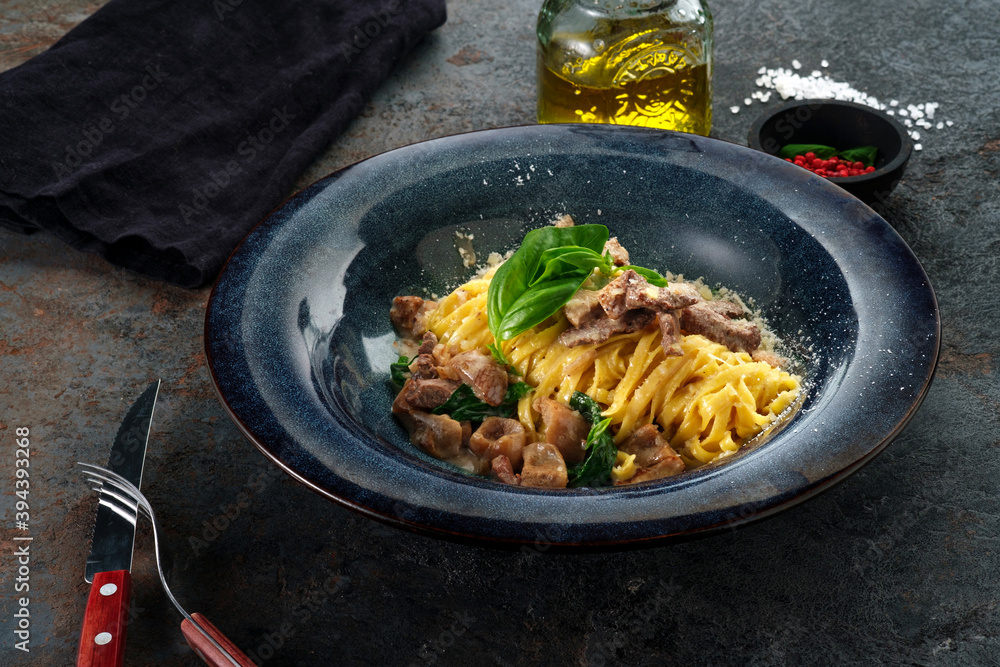 Wall mural tagliatelle pasta with porcini mushrooms in cream sauce and parmesan cheese on stone table