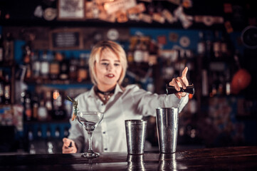 Girl bartender makes a cocktail behind the bar