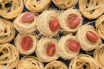 Pasta on the table, decorated with cherry tomatoes. Pasta on a dark stone background. Can be used as a background.