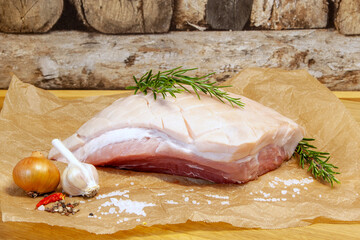 Raw Pork belly with sea salt, onion, garlic and herbs, rosemary. Roast salted pork, Bavarian crust roast. preparation for grooved pork celebration dinner, Christmas ham, Festival food. 