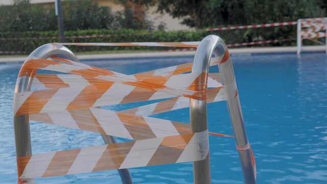 Closed slide in public swimming pool during coronavirus pandemic, caution tape, lockdown public space