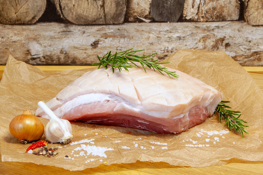 Raw Pork belly with sea salt, onion, garlic and herbs, rosemary. Roast salted pork, Bavarian crust roast. preparation for grooved pork celebration dinner, Christmas ham, Festival food. 