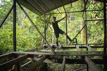 Hombre joven haciendo equilibrio en una construcción de una casa en medio de la naturaleza