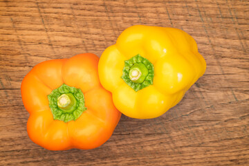 fresh orange and yellow peppers on an antique cutting board