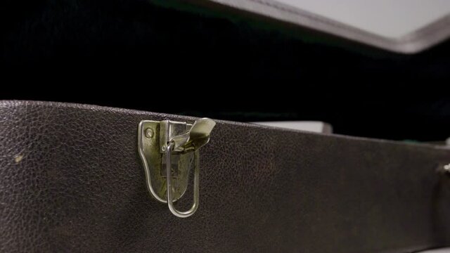 Guitar player opens brown vintage guitar case. Guitar case is made with green wool. Metallic latches. Guitar player school. White background. 4k