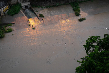 River canal in a big city. Sewage after rain carries garbage along the river.