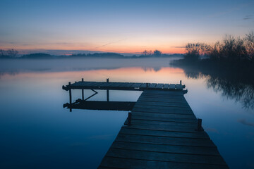 Wooden platform on a calm lake after sunset
