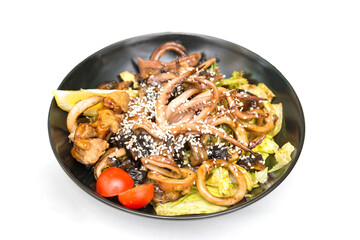 Octopus salad with lemon and spices on a black plate, top view, on a white plate, tentacles, grilled squid, appetizer. Isolated.
