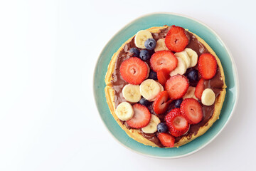 blue plate with mixed fruit and chocolate spread on waffle - 394399281