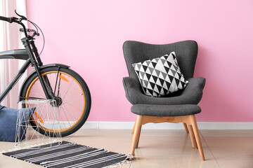 Stylish armchair and ottoman with bicycle in interior of room