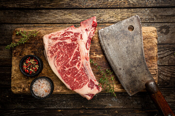 Raw fresh meat T-bone beef Steak and butcher knife on wooden background, top view