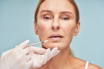 Doctor in protective gloves doing lip augmentation procedure