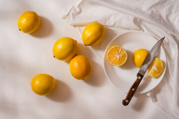 Fresh yellow lemons in a white plate on a white background. Half a lemon.