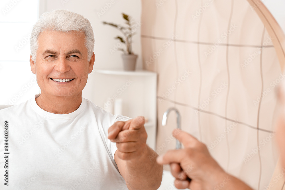 Wall mural Happy senior man near mirror in bathroom