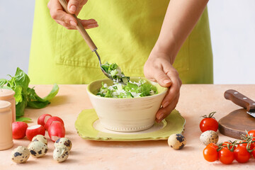 Woman mixing rice salad with vegetables on table