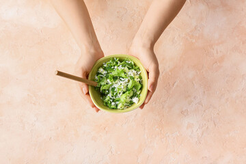 Woman holding  rice salad on color background