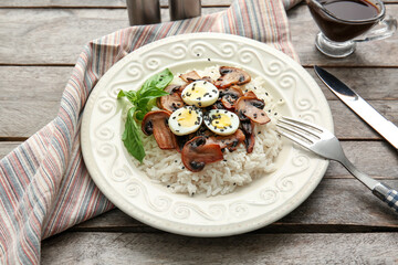 Plate of delicious rice with mushrooms on wooden background