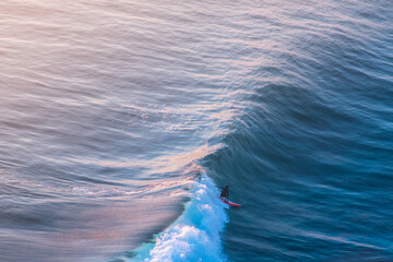 Bali, Indonesia, 2019. Surfer is catching wave on sunset