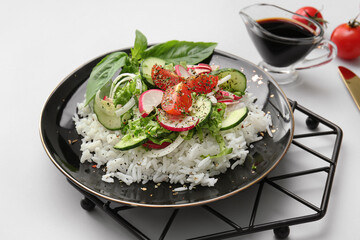 Plate of delicious rice salad with vegetables on light background