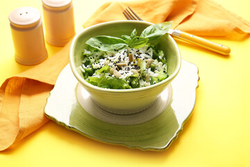 Bowl of delicious rice salad with vegetables on color background