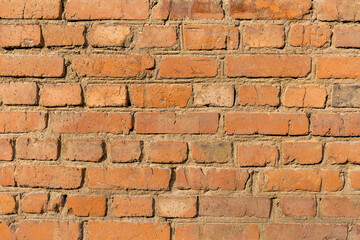Rough, uneven texture old brick red wall close up.
