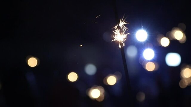Fireworks sparkler illuminated by lights in the background