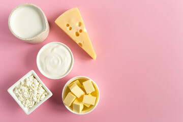 Healthy food most common products from milk are butter, cheese, milk, sour cream, cottage cheese on a pink paper background flat lay with copy space.