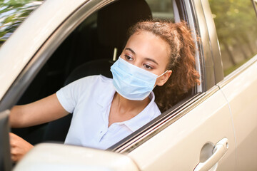 African-American female driver wearing medical mask in car