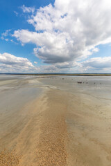 Obraz premium Group of hikers in the bay at low tide. Hike in the bay with a knowledgeable guide. Mont Saint-Michel , Normandy, France