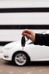 keys in hand on a background of white cars and black and white buildings