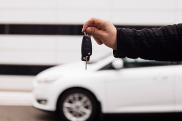 keys in hand on a background of white cars and black and white buildings
